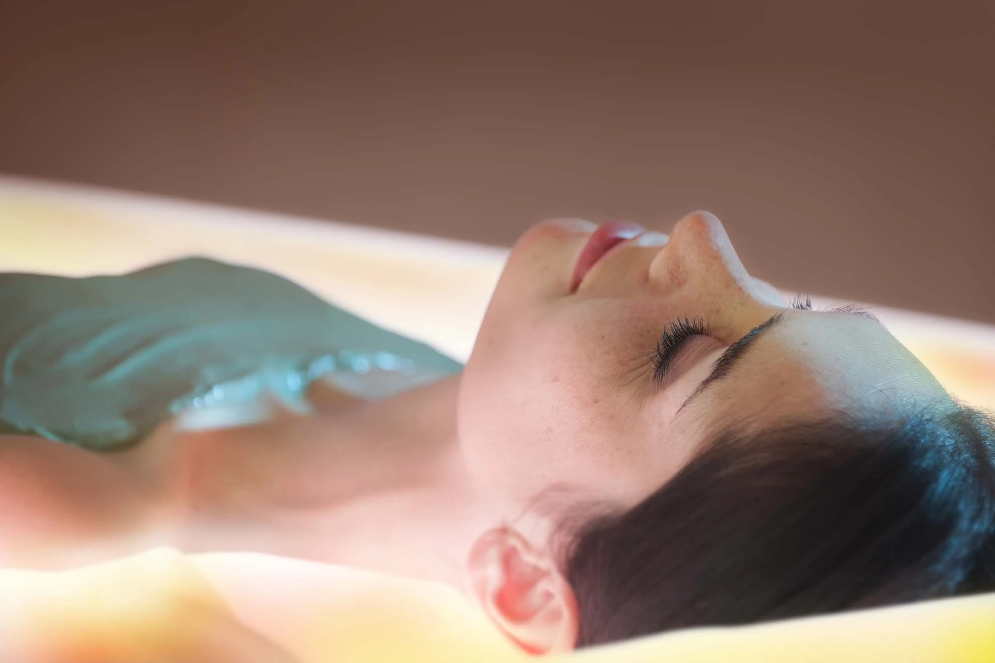 Femme recevant un soin d'enveloppement thermo-actif aux algues sur lit hydrosensoriel